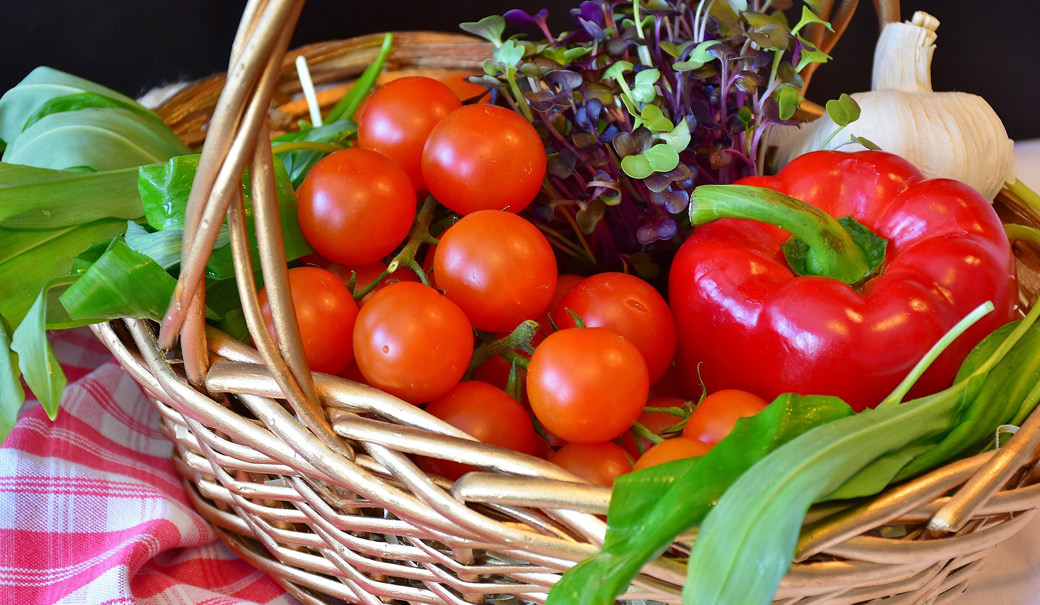 ein Korb mit frischem Gemüse wie Paradeiser und Paprika